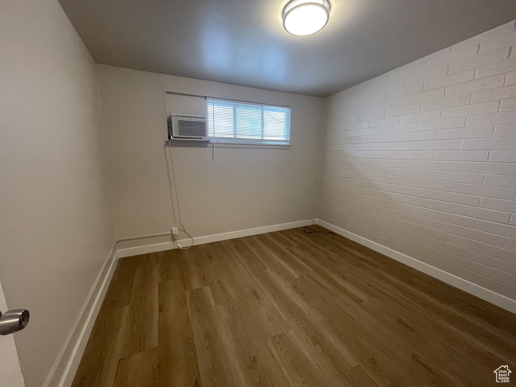 Empty room with baseboards, wood finished floors, and brick wall