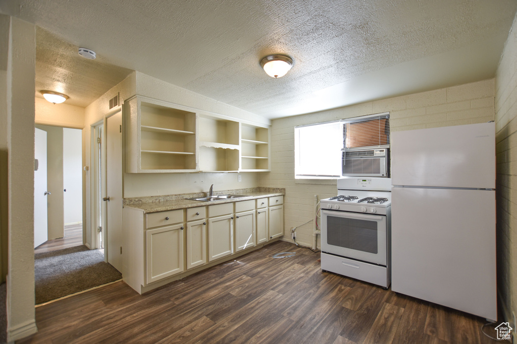 Kitchen with open shelves, white appliances, a textured ceiling, a sink, and dark wood finished floors