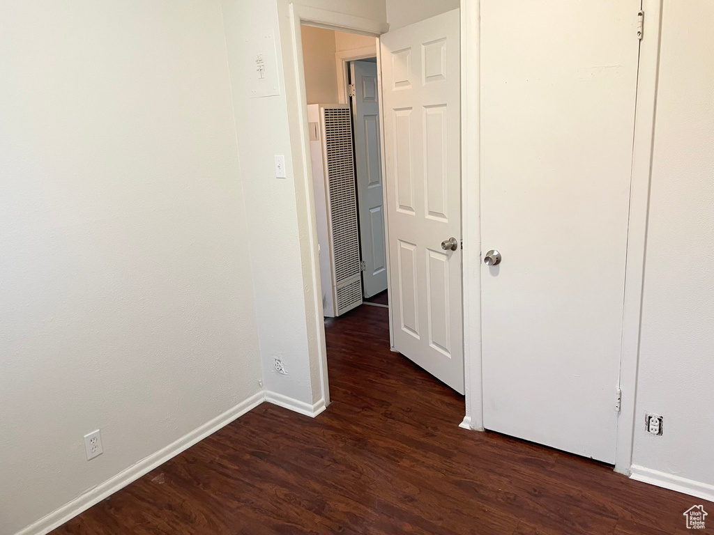 Interior space featuring baseboards, a heating unit, and dark wood-style floors