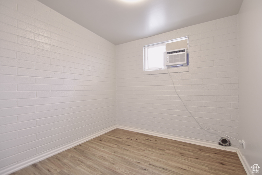 Unfurnished room featuring light wood-style floors, baseboards, and an AC wall unit