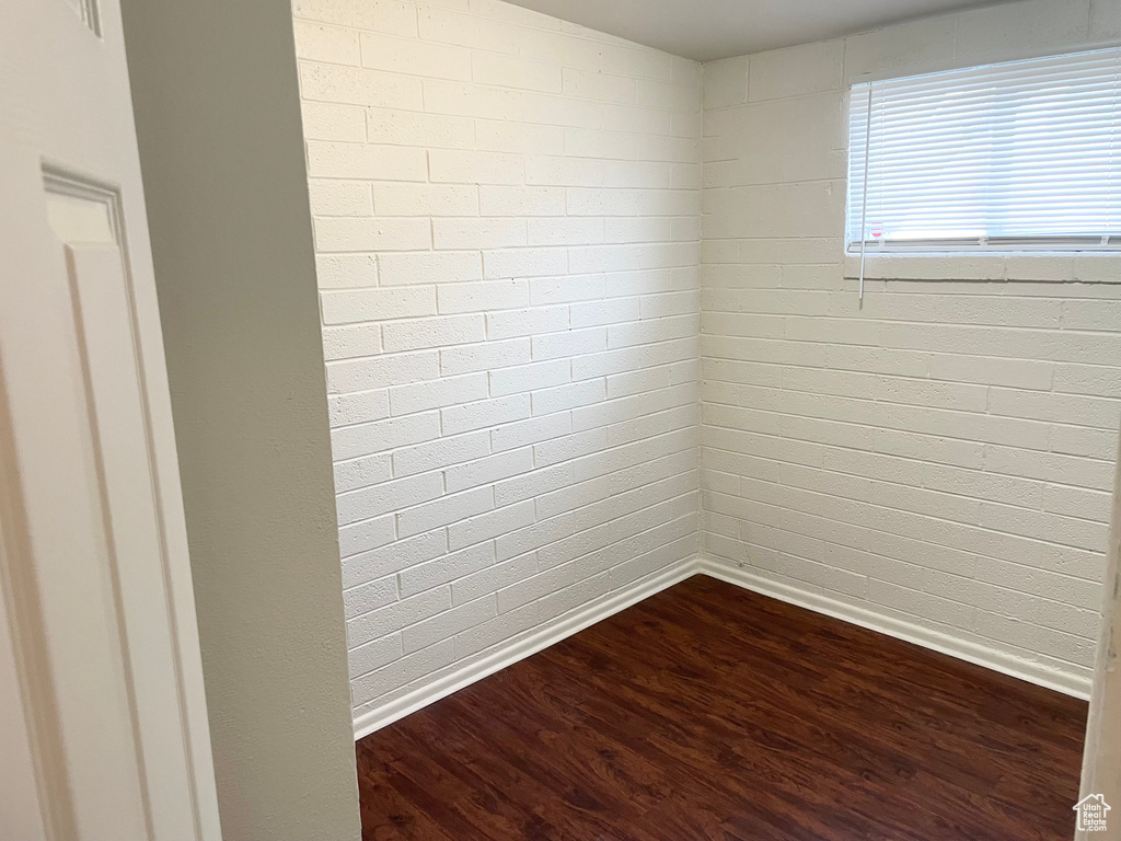 Unfurnished room with baseboards and dark wood-type flooring