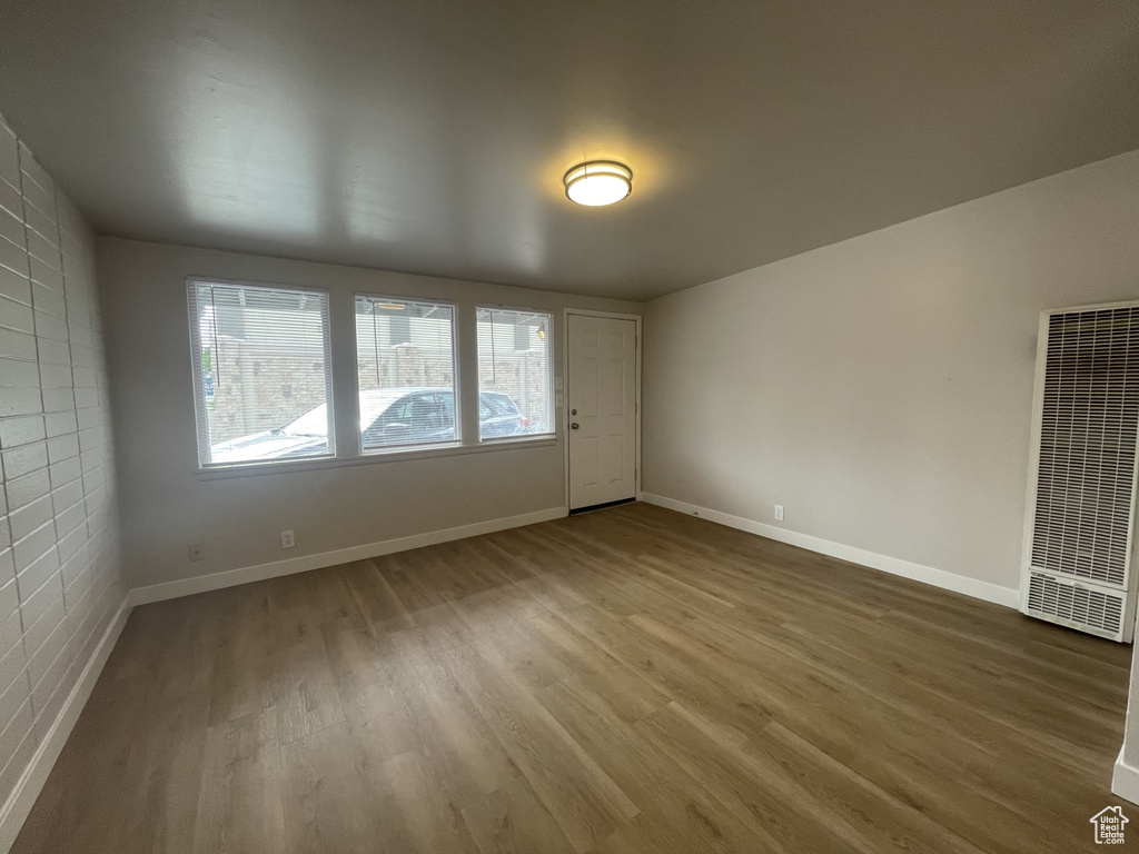 Unfurnished room with baseboards, a heating unit, and wood finished floors