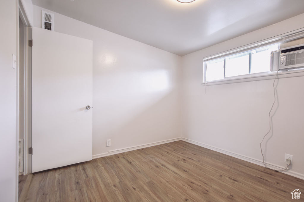 Unfurnished room with baseboards, visible vents, and wood finished floors