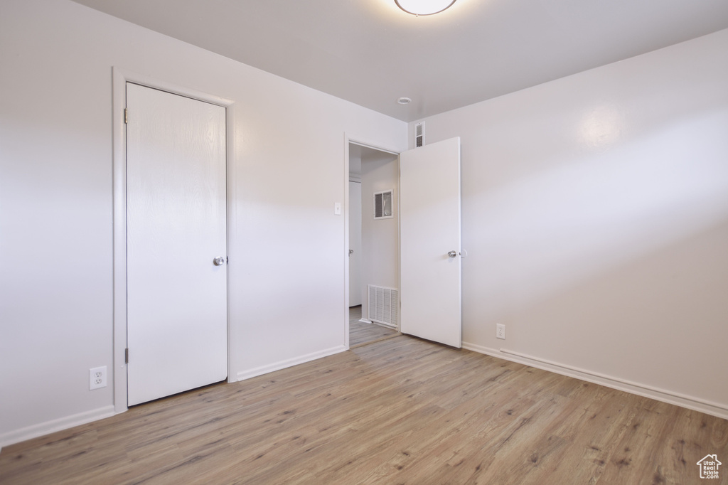 Unfurnished bedroom with baseboards, wood finished floors, and visible vents