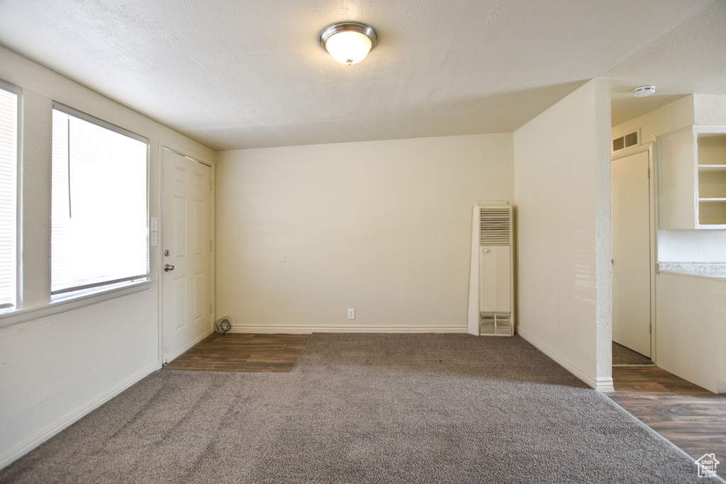 Carpeted spare room featuring visible vents, a heating unit, and baseboards