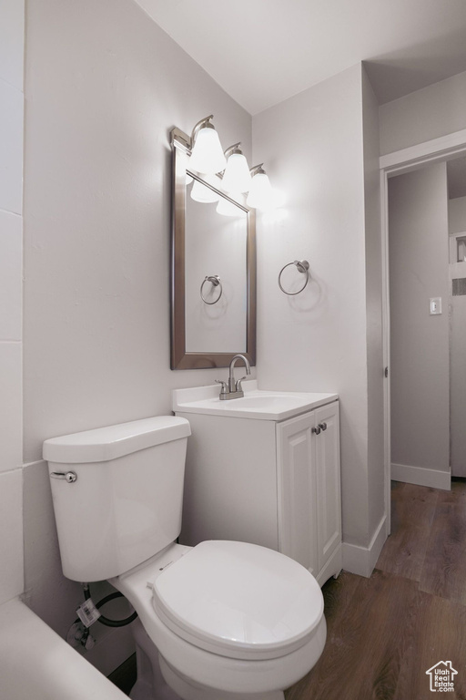 Half bath with vanity, baseboards, toilet, and wood finished floors