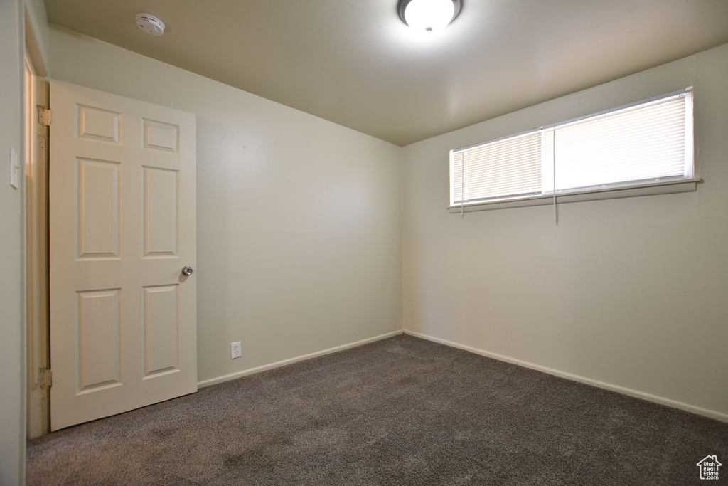 Unfurnished room featuring dark carpet and baseboards