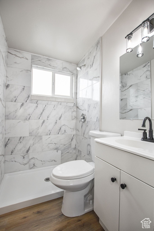 Bathroom featuring vanity, walk in shower, wood finished floors, and toilet