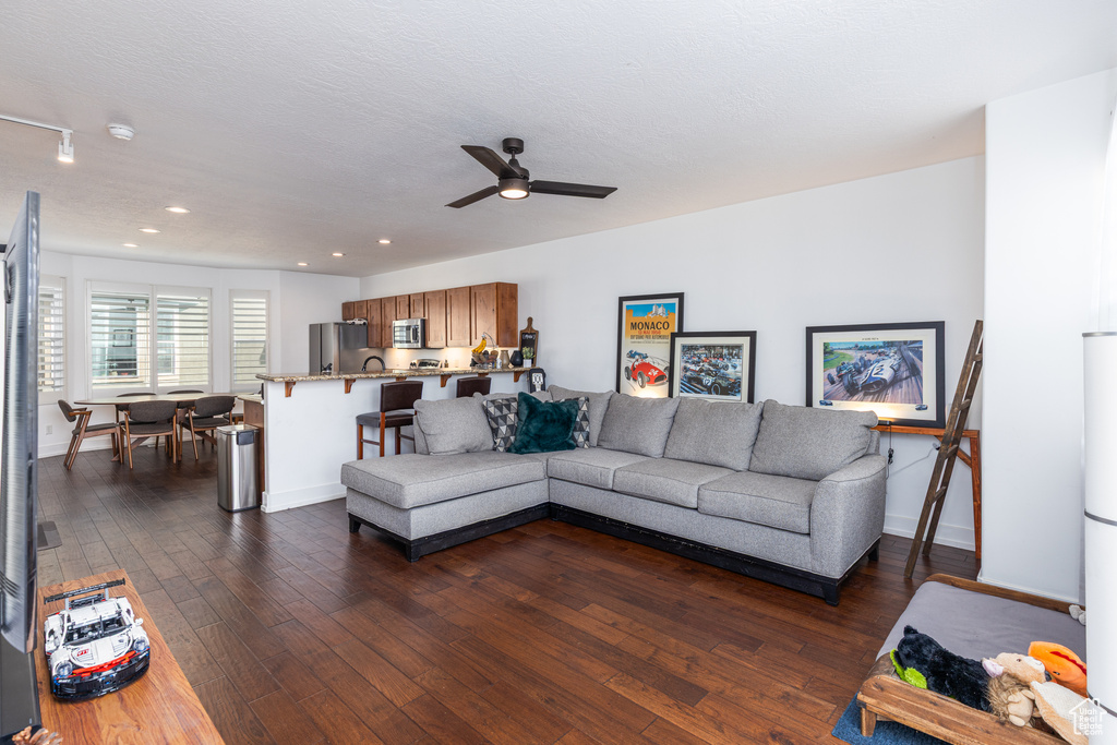Living area featuring a ceiling fan, baseboards, dark wood finished floors, and recessed lighting