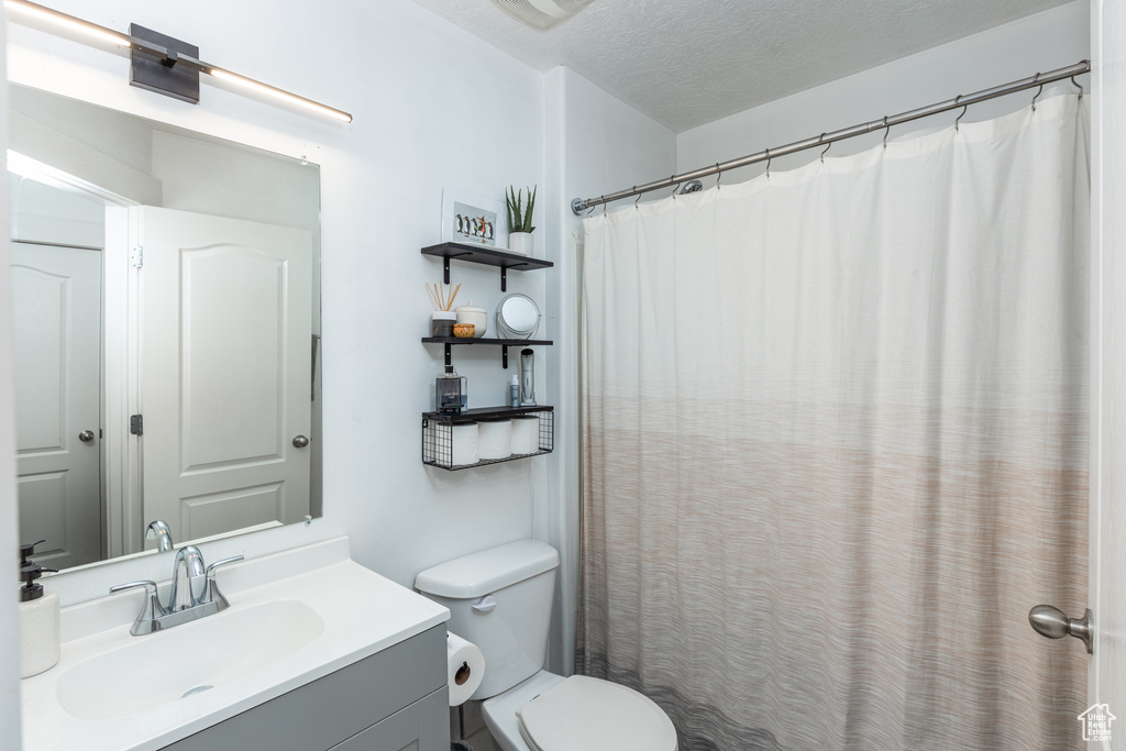 Bathroom with toilet, a textured ceiling, and vanity
