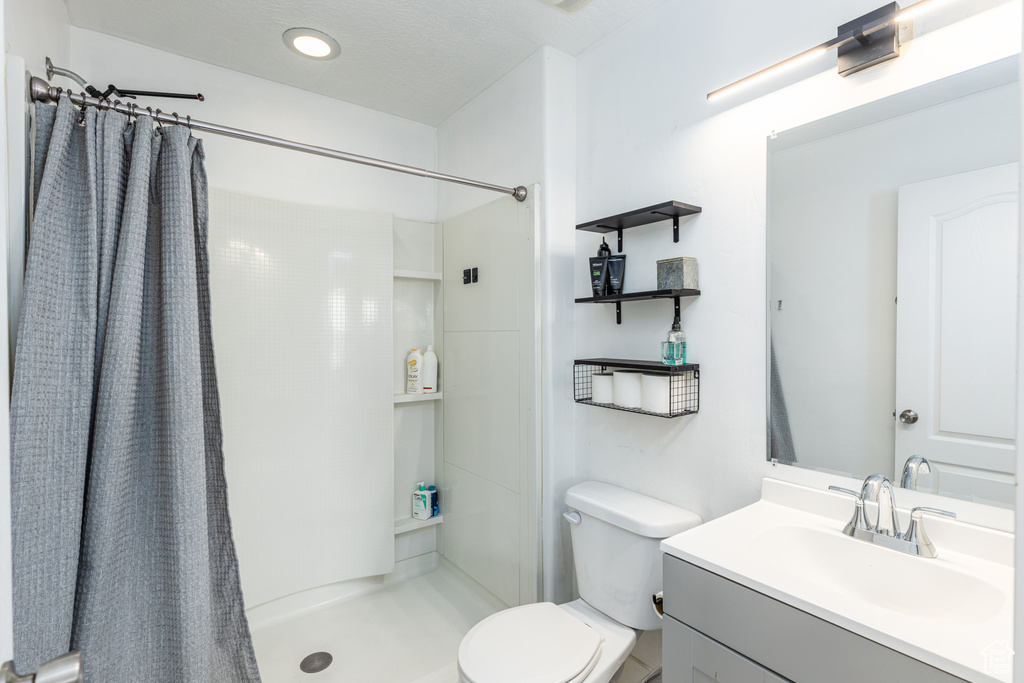 Full bath with recessed lighting, a shower with shower curtain, toilet, and vanity