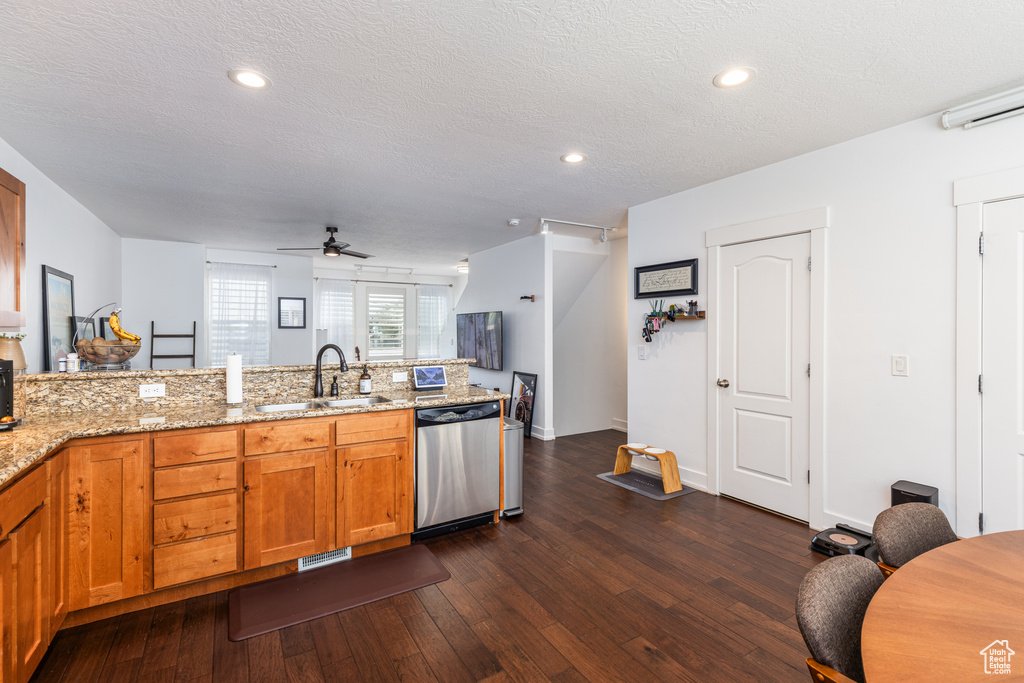 Kitchen with brown cabinets, stainless steel dishwasher, a sink, ceiling fan, and a peninsula