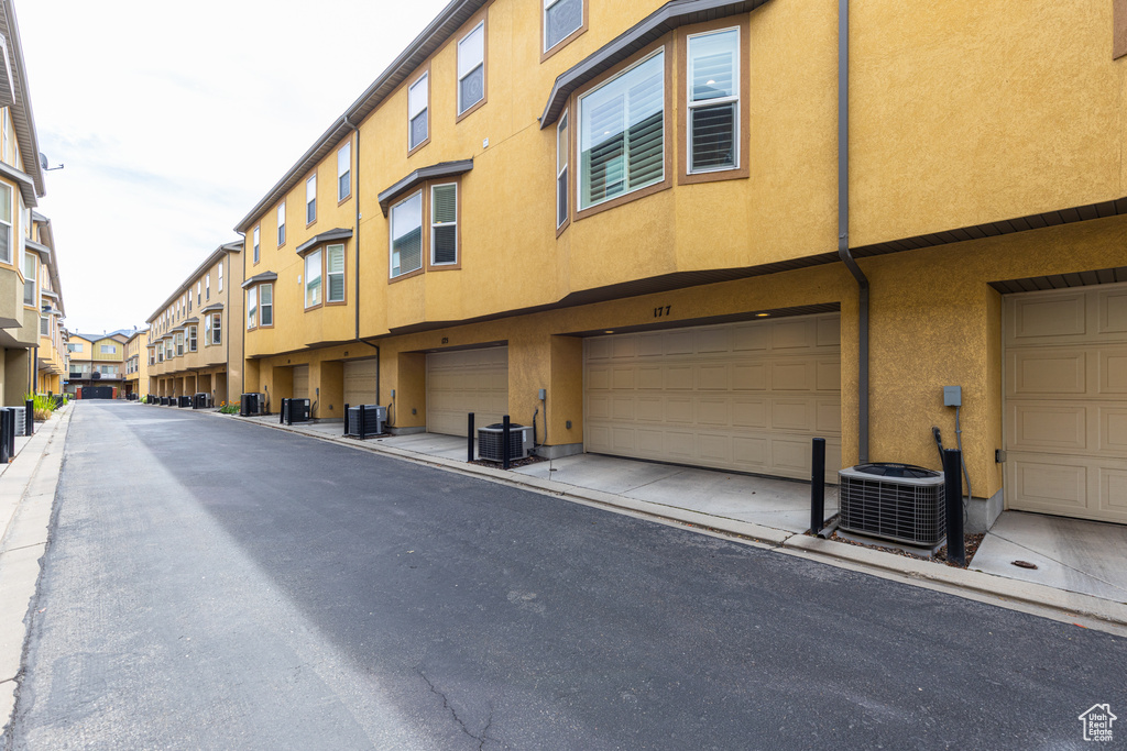View of property featuring a garage, a residential view, and central air condition unit