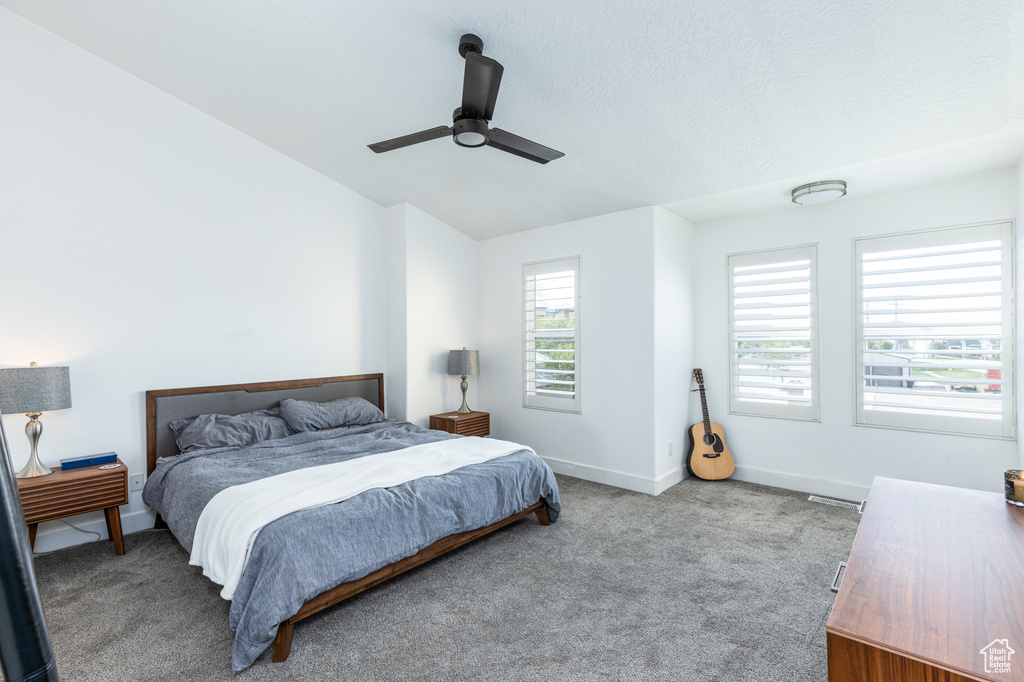 Bedroom featuring a ceiling fan, baseboards, vaulted ceiling, and carpet floors