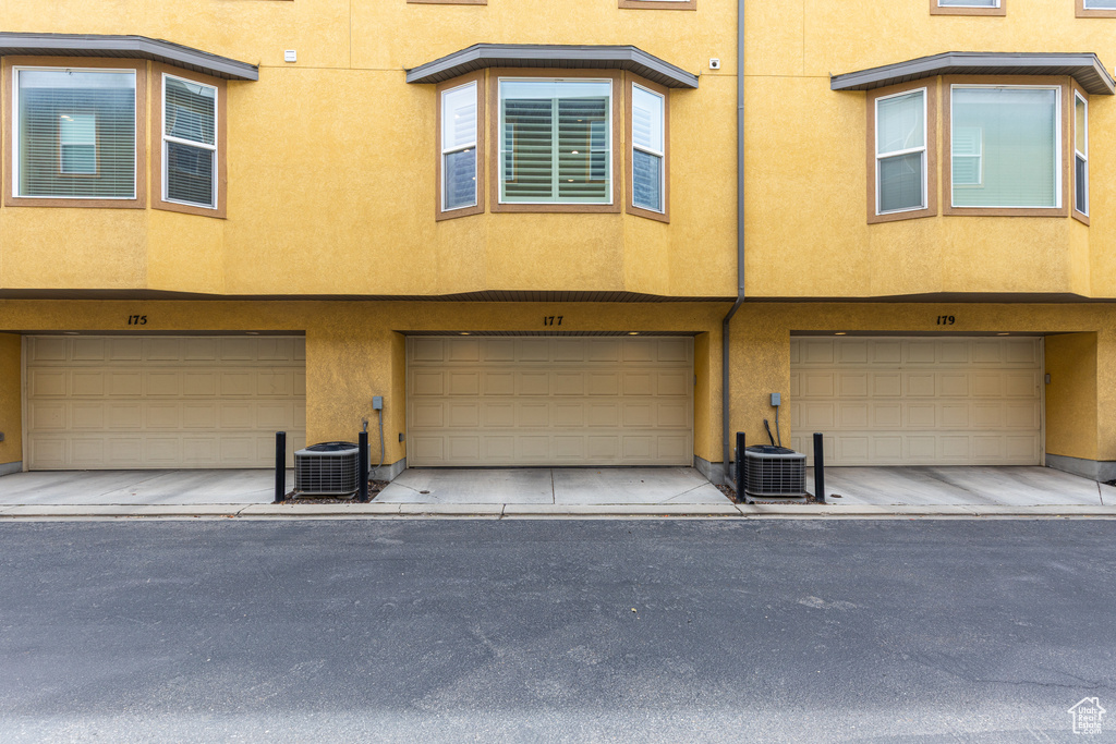 View of front of house featuring stucco siding, central AC unit, and an attached garage