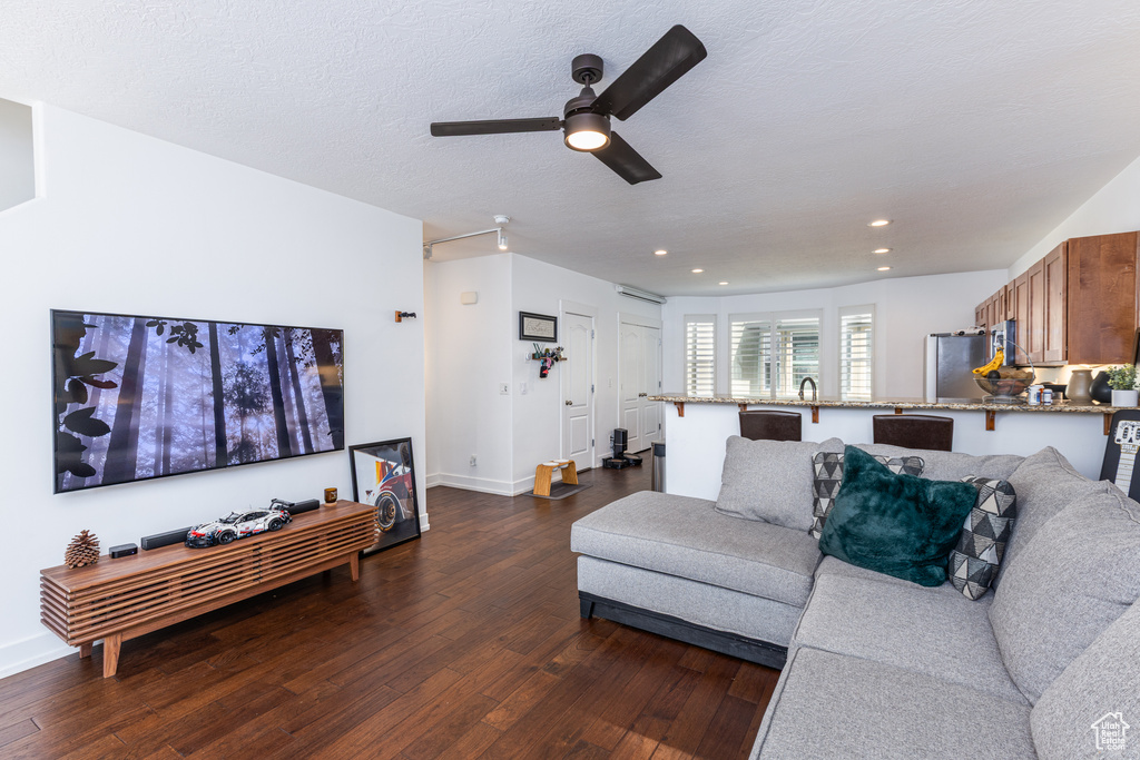 Living room with dark wood-style flooring, ceiling fan, recessed lighting, and baseboards