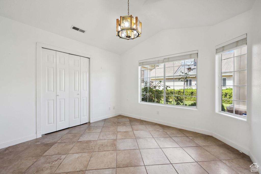Unfurnished bedroom with a notable chandelier, baseboards, lofted ceiling, visible vents, and a closet