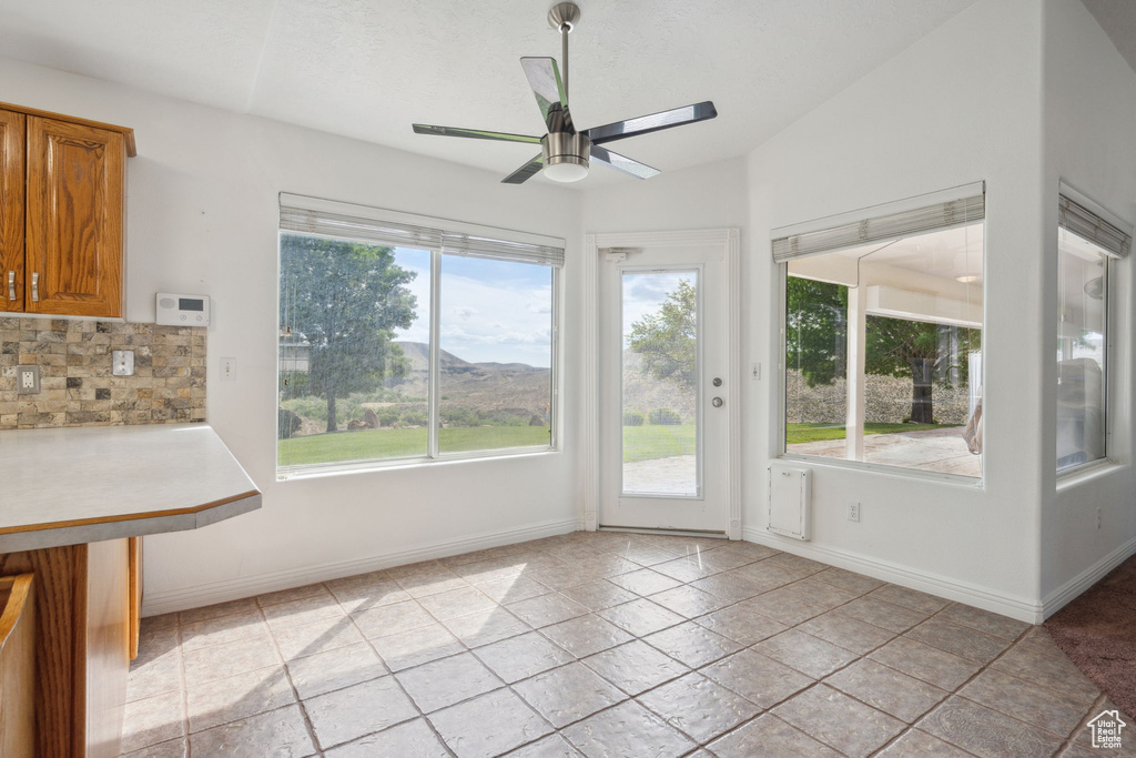Interior space with baseboards, ceiling fan, and a wealth of natural light