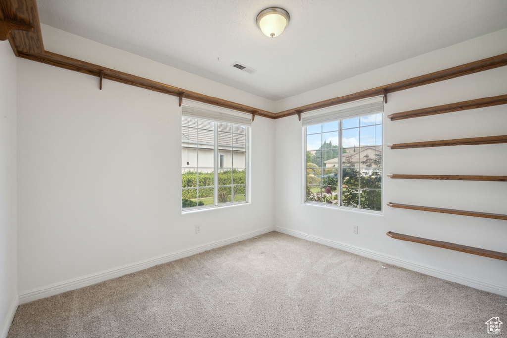 Carpeted empty room with visible vents and baseboards