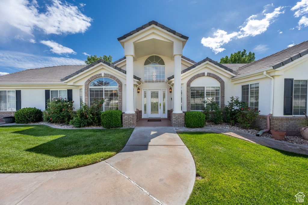 Exterior space with stucco siding, a front lawn, and brick siding