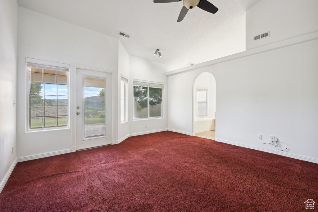 Carpeted empty room with visible vents, a ceiling fan, baseboards, and arched walkways