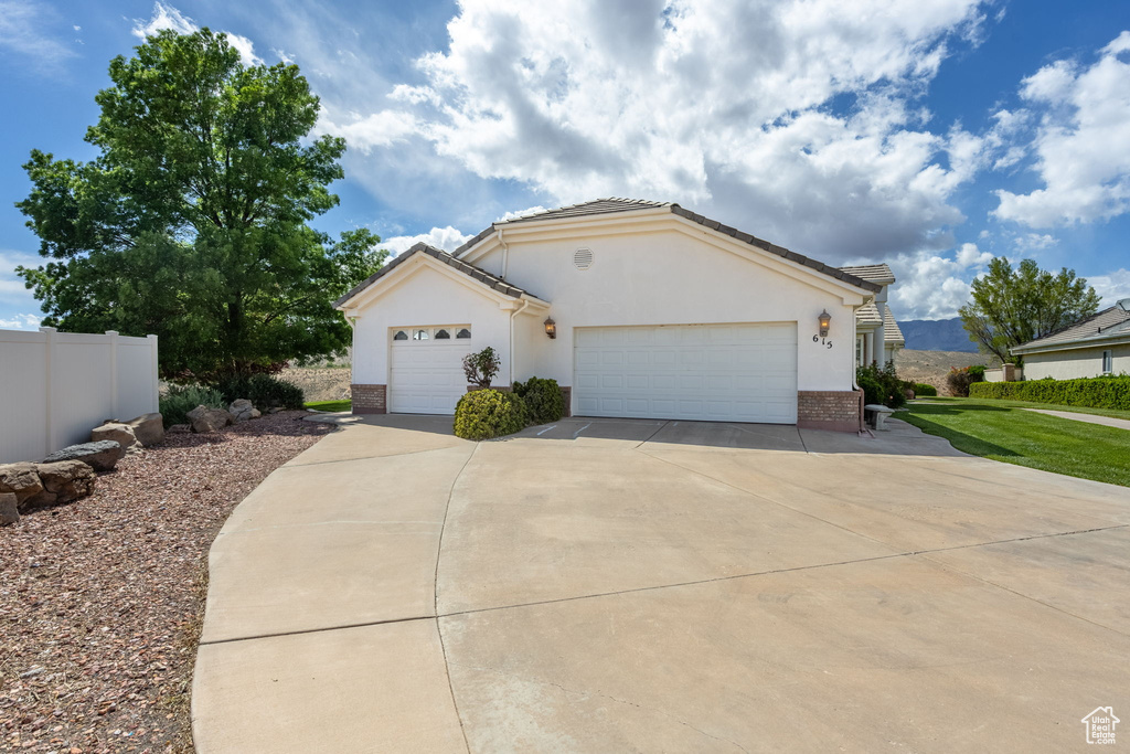 Ranch-style home featuring brick siding, an attached garage, driveway, and stucco siding
