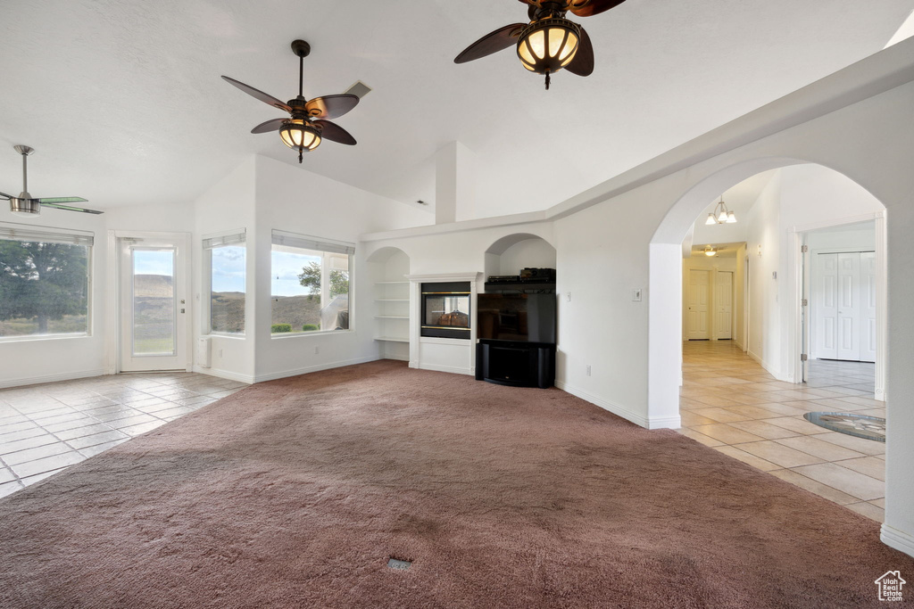 Unfurnished living room featuring tile patterned floors, baseboards, a ceiling fan, and carpet floors