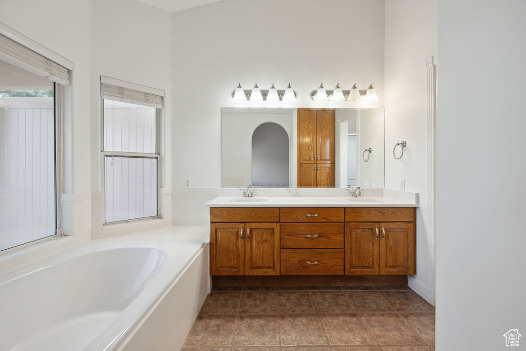 Full bathroom with double vanity, a sink, and a bath