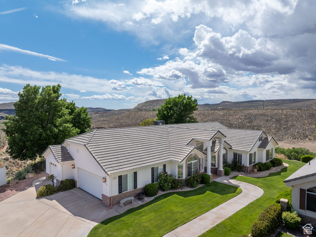 View of front facade with a front lawn, stucco siding, a mountain view, driveway, and a tile roof
