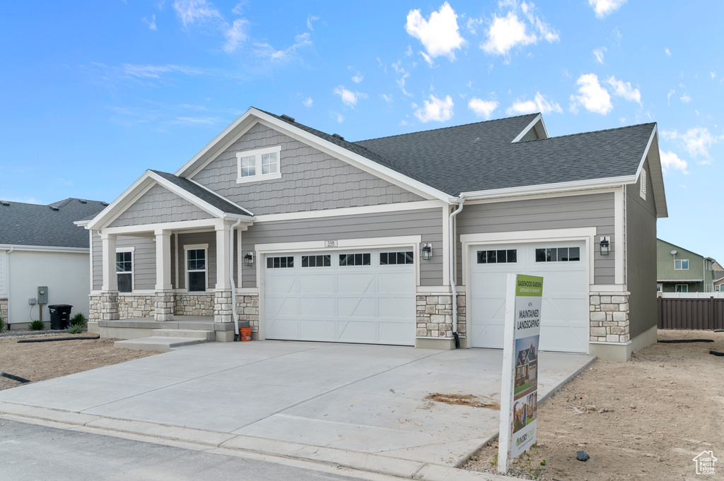 Craftsman house with stone siding, a garage, and driveway