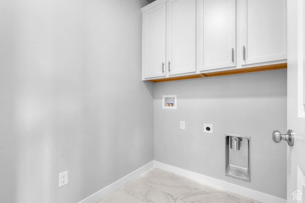 Laundry area featuring cabinet space, hookup for a washing machine, electric dryer hookup, baseboards, and light marble finish flooring