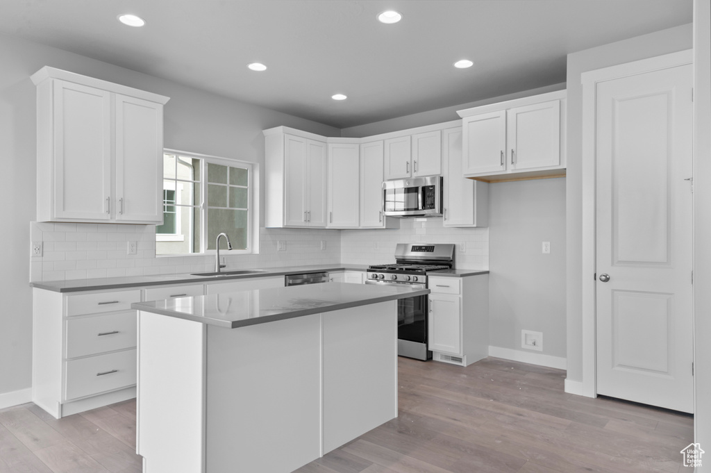 Kitchen featuring stainless steel appliances, a sink, light wood-type flooring, white cabinets, and recessed lighting