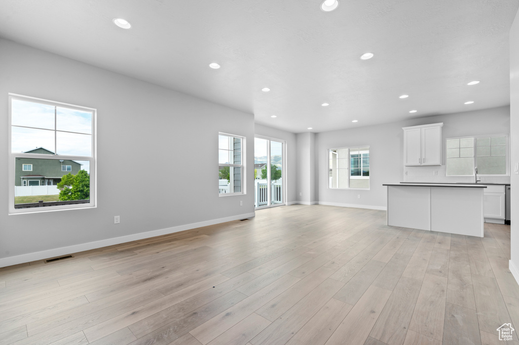 Unfurnished living room featuring recessed lighting, baseboards, and light wood-style flooring