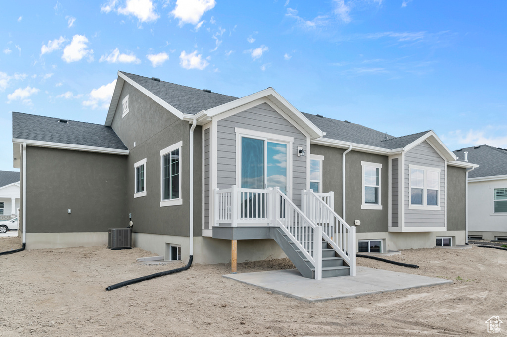 Rear view of property featuring cooling unit, roof with shingles, and stucco siding