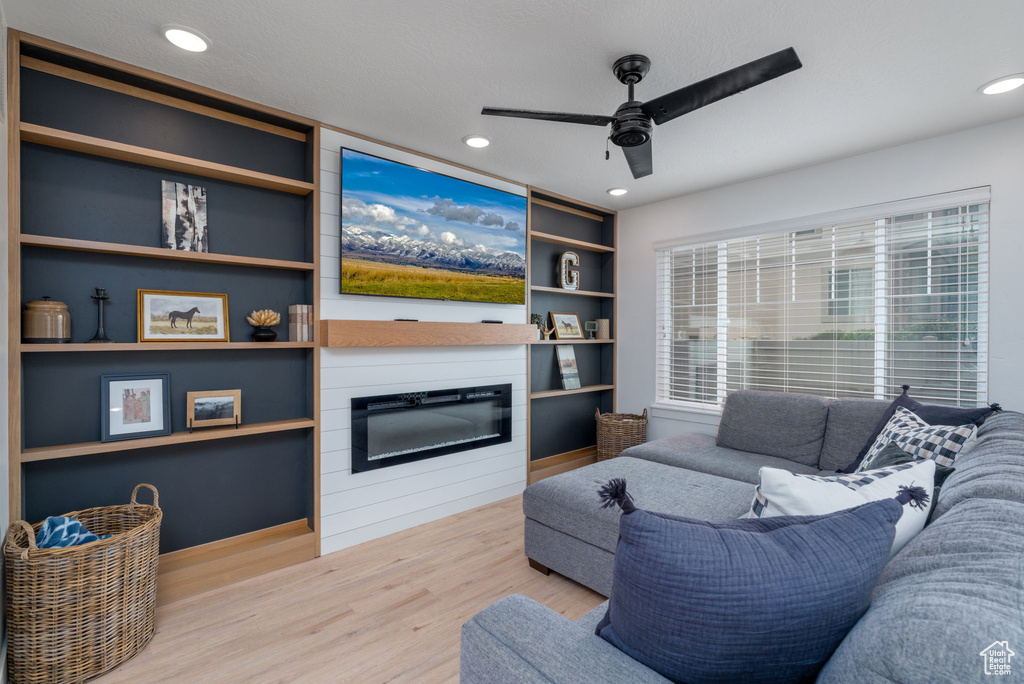 Living room featuring a large fireplace, ceiling fan, recessed lighting, and wood finished floors