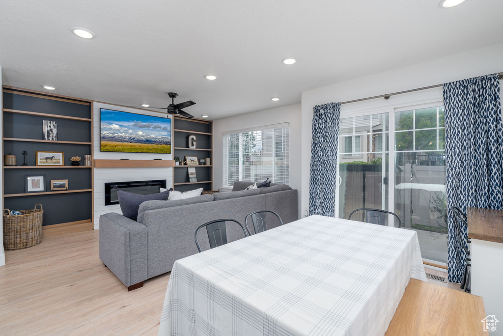 Dining area featuring recessed lighting, a glass covered fireplace, a healthy amount of sunlight, and light wood finished floors
