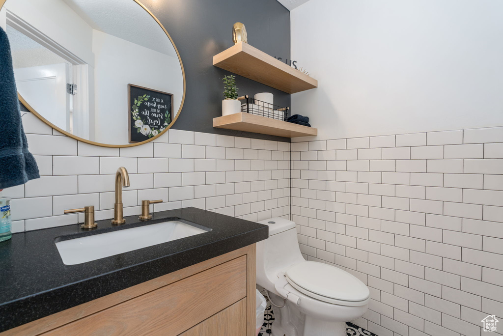 Bathroom featuring toilet, tile walls, and vanity