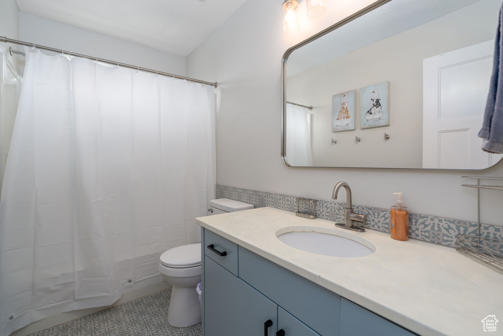 Bathroom with toilet, a shower with curtain, and vanity