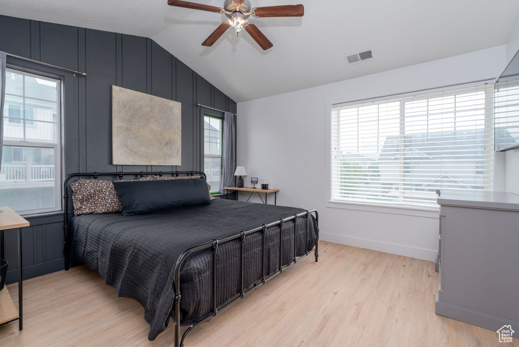Bedroom featuring visible vents, multiple windows, vaulted ceiling, and light wood-type flooring