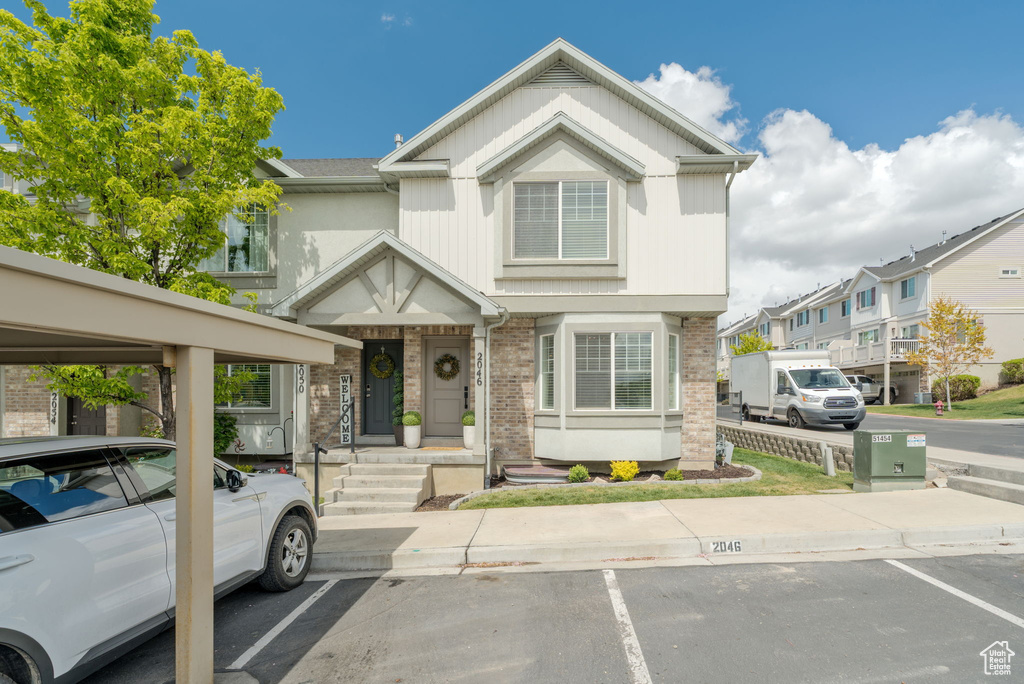 Townhome / multi-family property featuring uncovered parking and brick siding