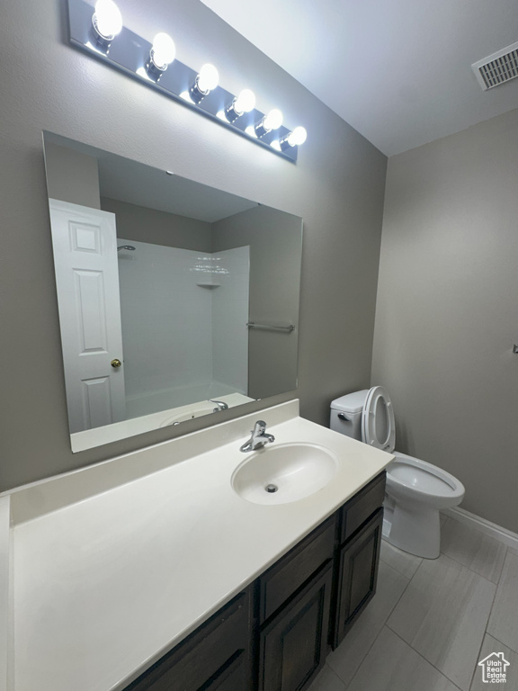 Bathroom featuring toilet, visible vents, a shower, and vanity