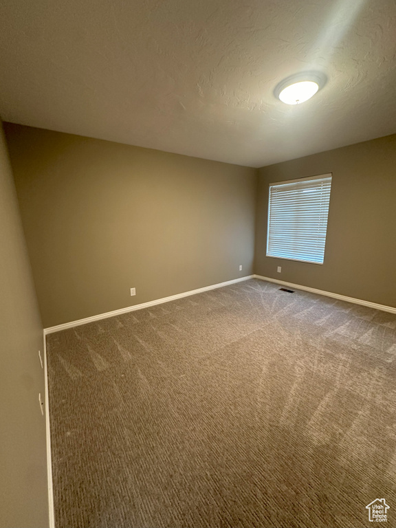Carpeted spare room with baseboards and visible vents