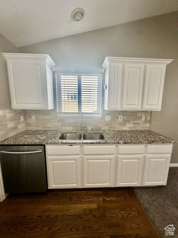 Kitchen featuring a sink, light stone counters, vaulted ceiling, and dishwasher