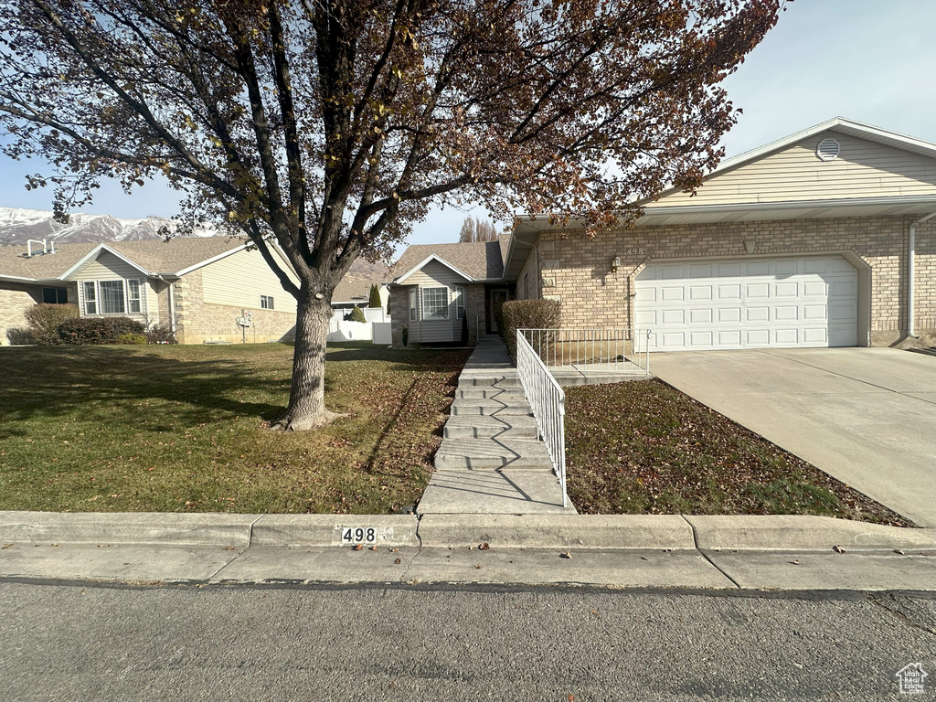 Ranch-style house with an attached garage, a front yard, driveway, and brick siding