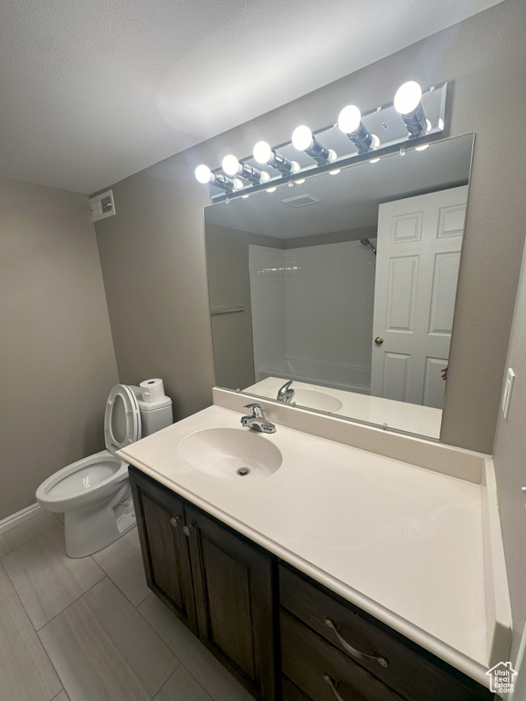 Bathroom with visible vents, vanity, toilet, baseboards, and walk in shower