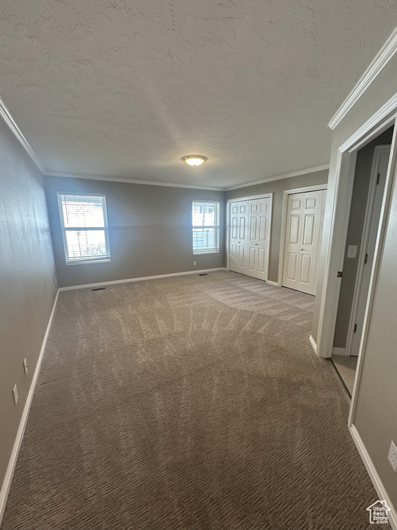 Interior space with crown molding, carpet flooring, multiple closets, and baseboards