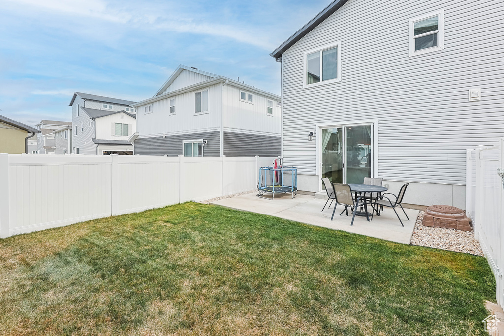 Back of house featuring a yard, fence, a trampoline, and a patio area