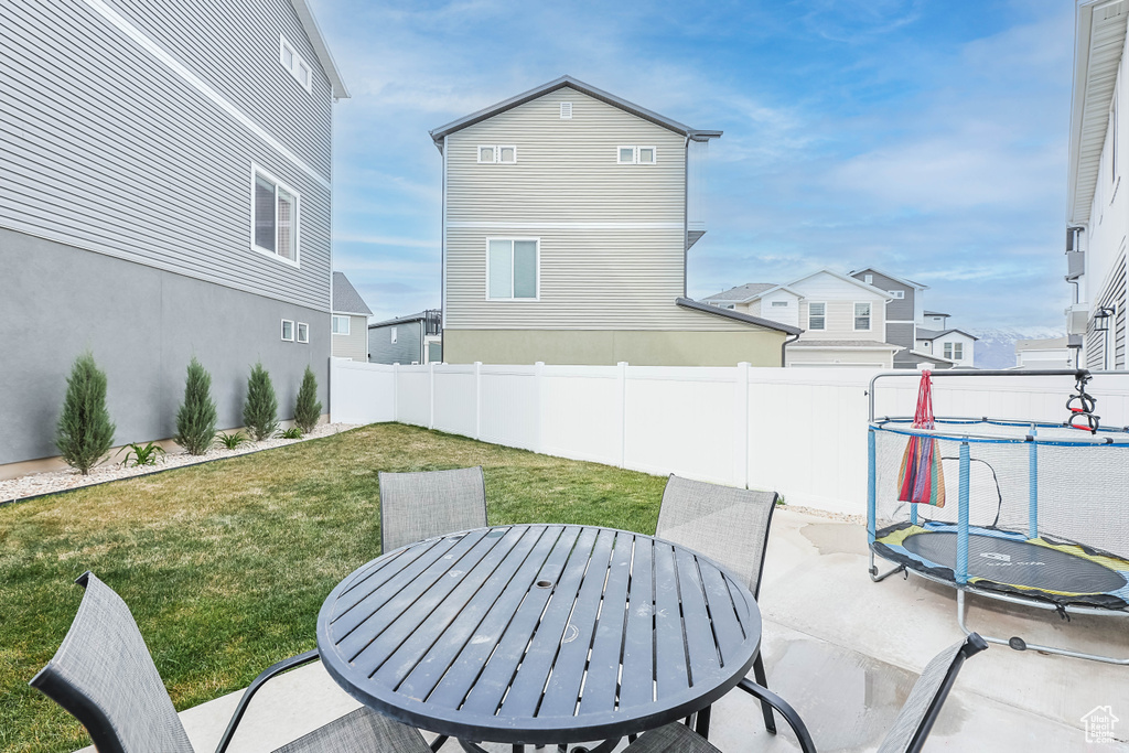 View of patio with a fenced backyard, outdoor dining area, and a trampoline