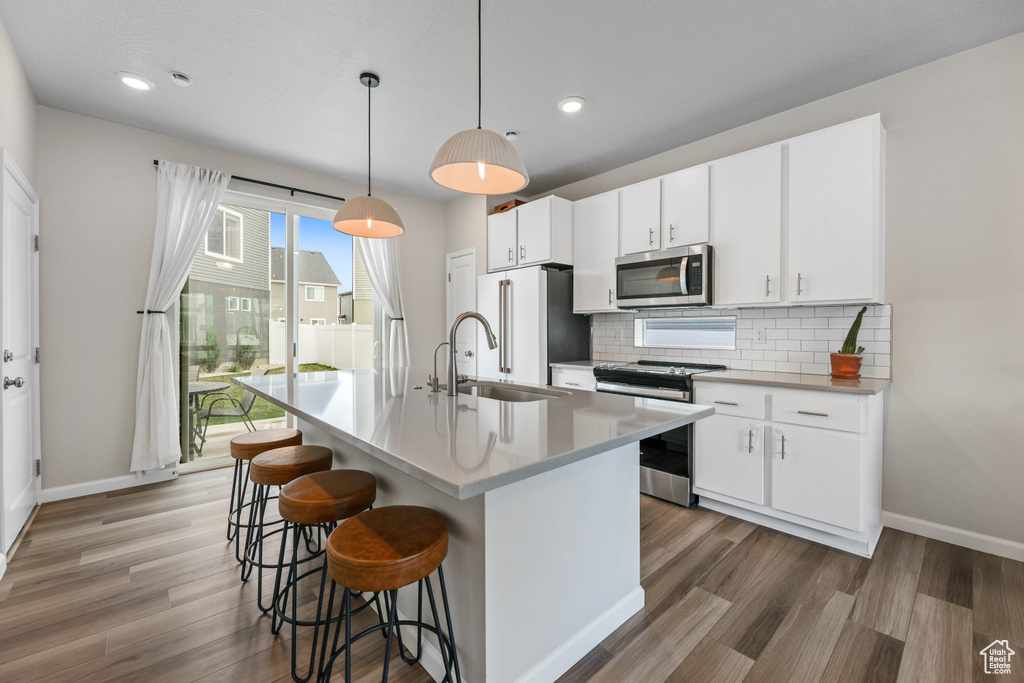 Kitchen with a kitchen breakfast bar, baseboards, appliances with stainless steel finishes, and light wood finished floors