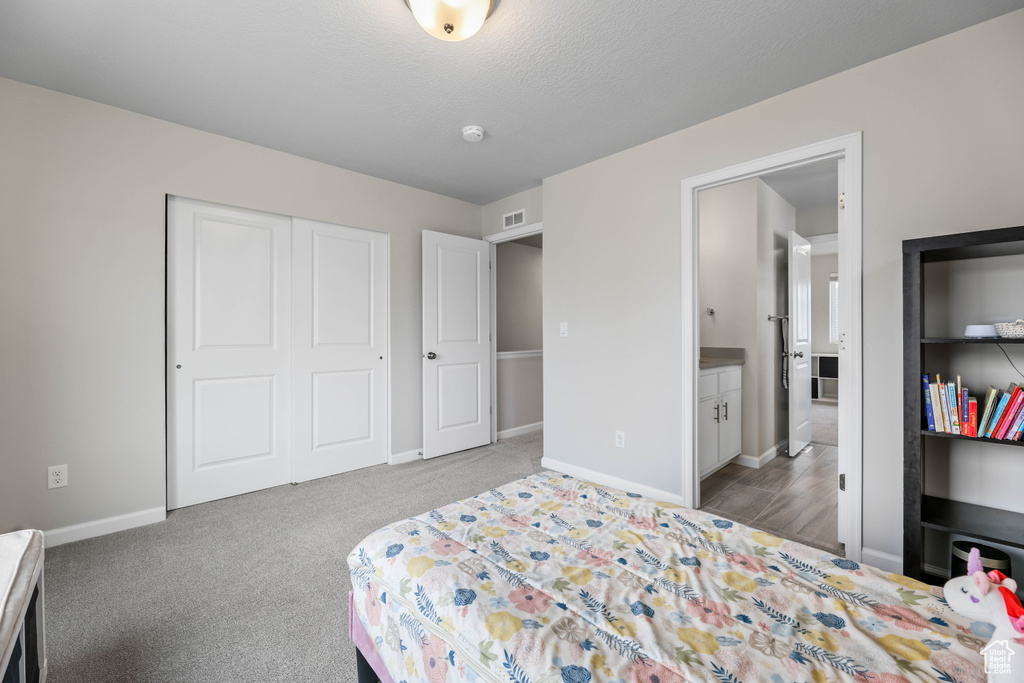 Carpeted bedroom with a closet, baseboards, and ensuite bath